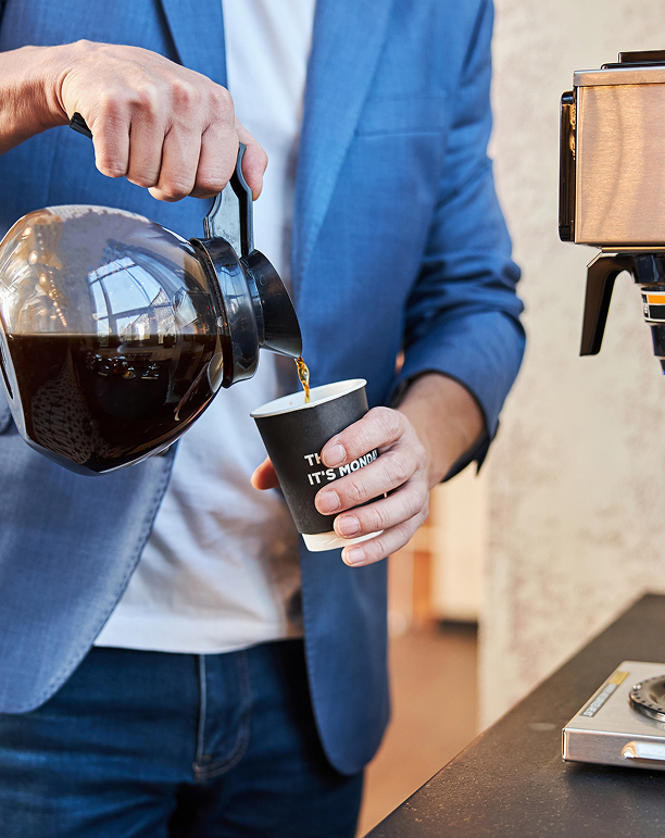 Image of an office worker pouring a mug of coffee